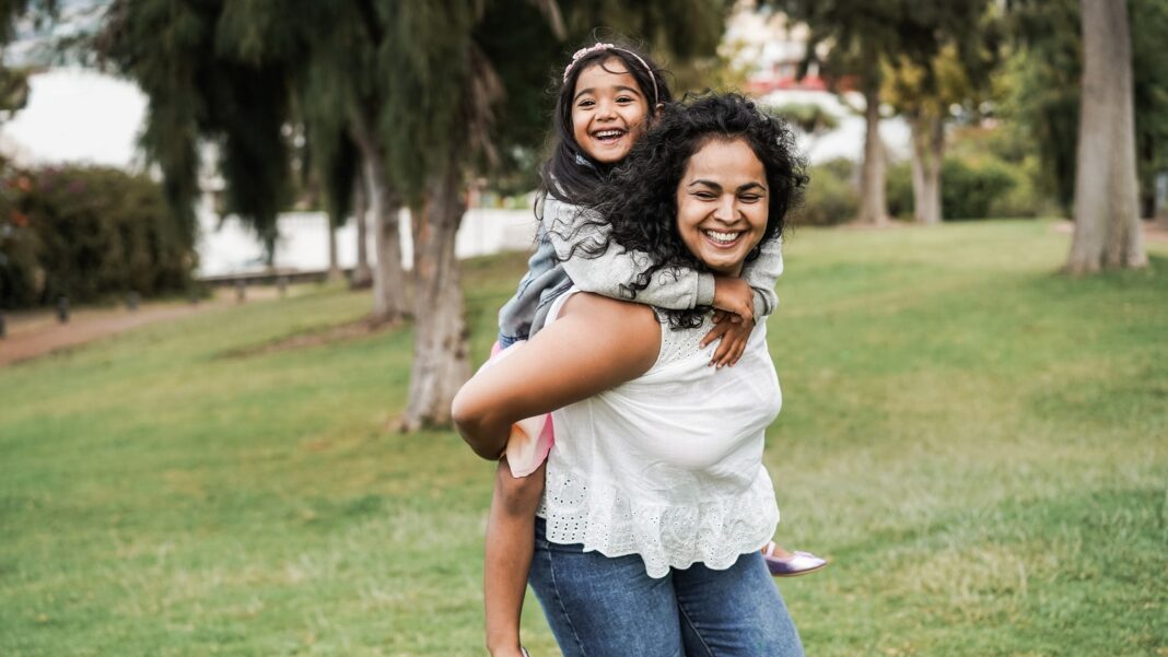 Happy indian mother having fun with her daughter outdoor - Focus on mother face